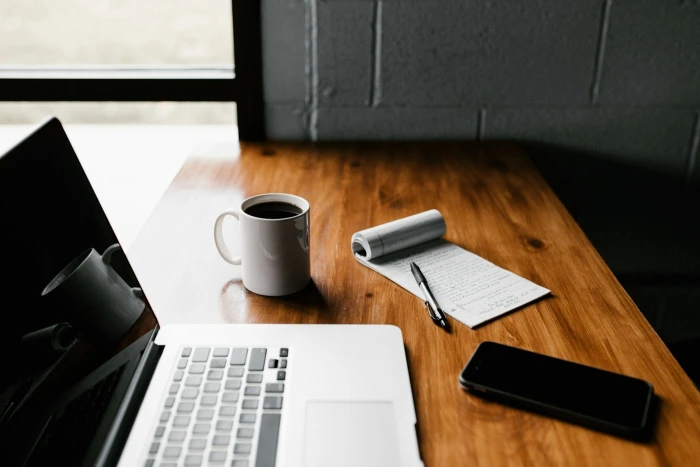 A blogger writing a post on a laptop at a wooden desk