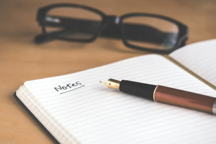 An open notebook with a handwritten outline next to a laptop